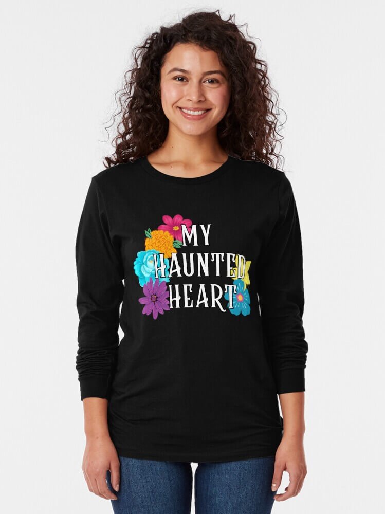 Person wearing a black long sleeve ‘My Haunted Heart’ shirt with colorful flowers and bold white lettering