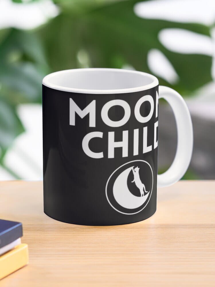 Moon Child mug on a wooden desk with a leafy plant blurred in the background.