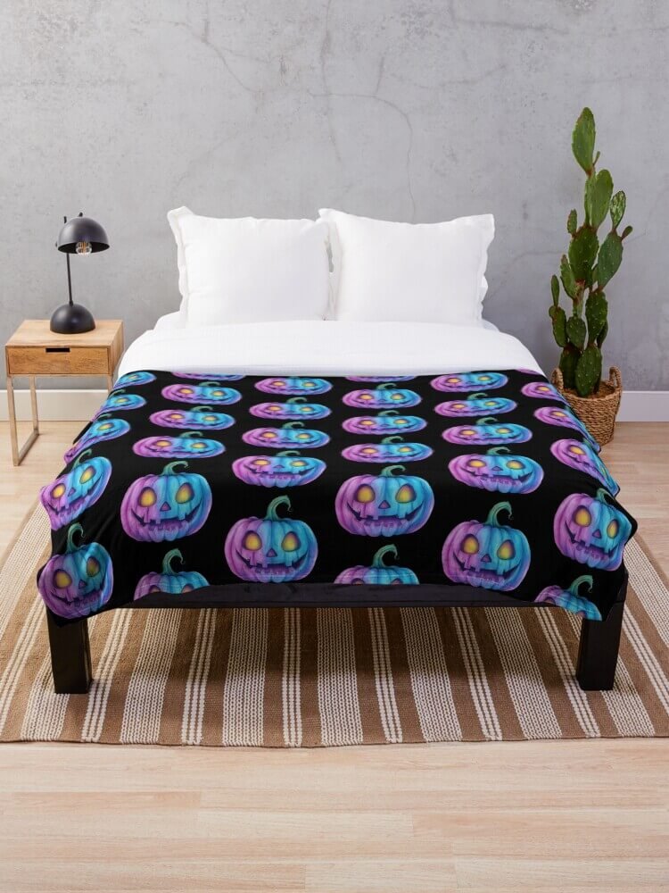 Black throw blanket with glowing pastel pumpkins spread across a white bed in a modern bedroom