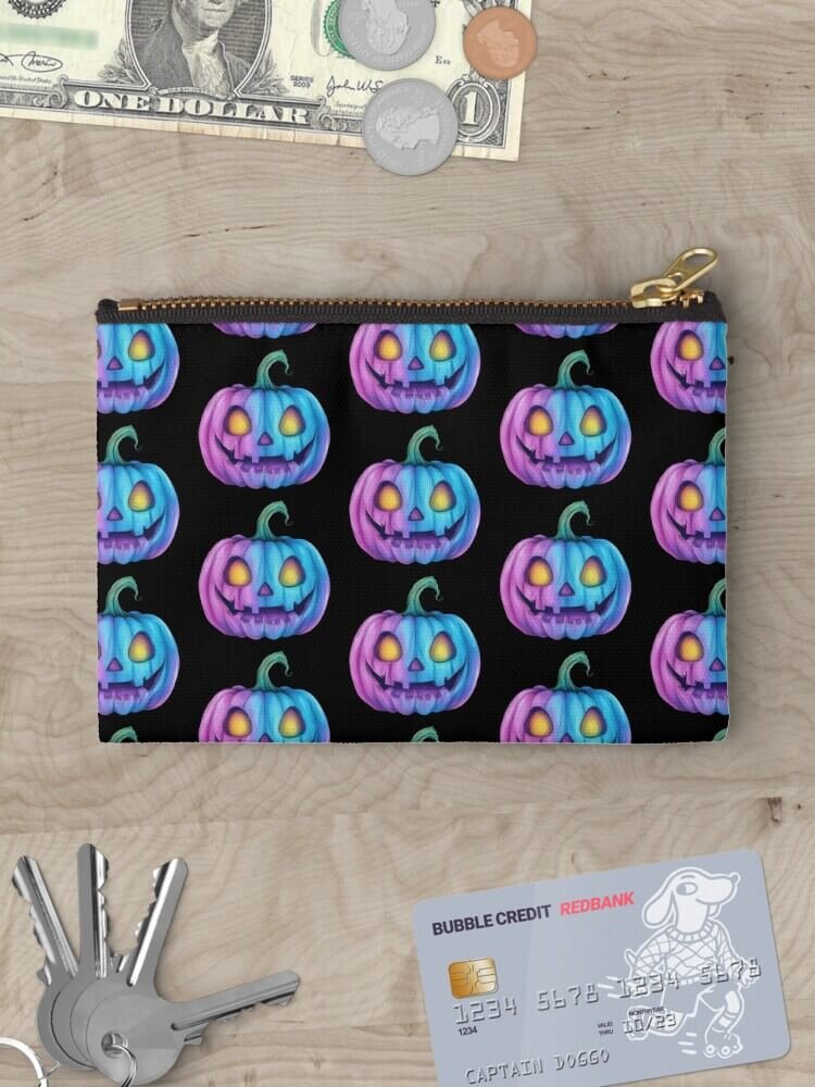 Pastel pumpkin glow zippered pouch on a wooden surface surrounded by cash, coins, keys and a credit card