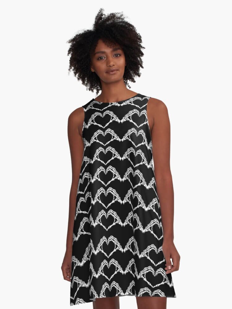 Person wearing a black A-line dress patterned with white skeleton hands forming heart shapes