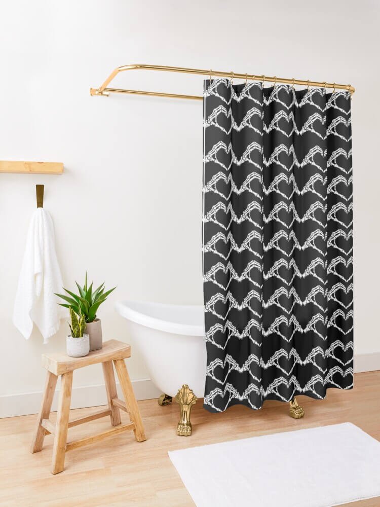 Black shower curtain with repeating white skeleton hand hearts hanging next to a clawfoot tub in a bright bathroom