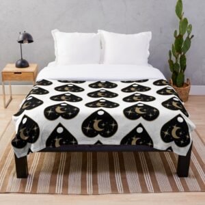 Golden Planchette throw blanket spread across a bed, featuring a bold black ouija planchette and gold moon pattern on white.